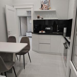 cocina con armarios blancos, mesa y sillas en Apartament Vip Chirie, en Chişinău