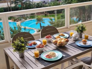 a table with breakfast food and a view of a pool at Gemelos 22 - Siroco in Benidorm