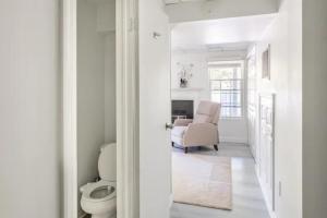 a white bathroom with a toilet and a chair at Newly Renovated Basement with Private Bathroom in Herndon