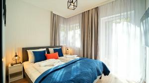 a bedroom with a bed with blue sheets and a window at Apartamenty EverySky - Słowackiego 5a-b in Karpacz