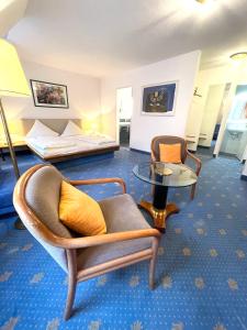 ラーベンスブルクにあるレブガルテンホテル シュールガッセのベッド、椅子、テーブルが備わるホテルルームです。