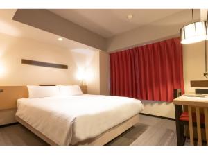 a bedroom with a large white bed and a red curtain at ibis Styles Kyoto Station in Kyoto