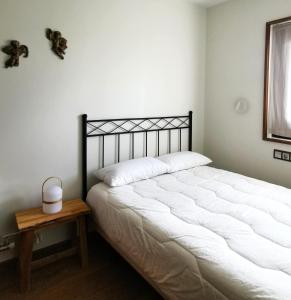 Un dormitorio con una gran cama blanca y una mesa en Casa adosada en Guils, en Guils de Cerdaña