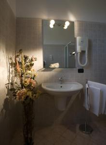 ein Badezimmer mit einem Waschbecken und einer Vase aus Blumen in der Unterkunft Hotel Scaligero in Sommacampagna