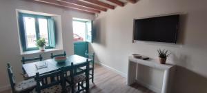 a dining room with a table and a tv on the wall at El balcón de Carmen in O Barqueiro