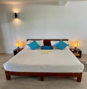 a bedroom with a large white bed with blue pillows at Rockside Cabanas Hotel in Unawatuna