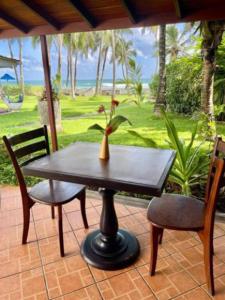 a table with two chairs and a vase with a plant at Rockside Cabanas Hotel in Unawatuna