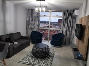 a living room with a couch and chairs and a window at Unit 802 Ten South in Durban