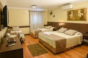 um quarto de hotel com duas camas e uma televisão em Hotel Premium em Gramado