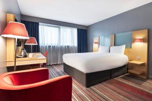 a hotel room with a large bed and a red chair at Park Inn by Radisson Cardiff City Centre in Cardiff