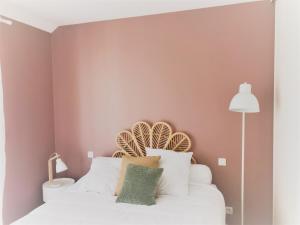 a bedroom with pink walls and a bed with white pillows at Appartement hyper centre, plage à pieds, 2 chambres, 4 personnes in Châtelaillon-Plage
