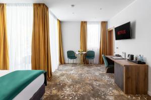 a hotel room with a bed and a desk and chairs at Tomis Garden Aparthotel Bucuresti in Bucharest