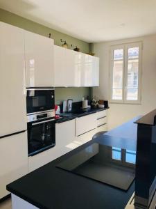 a kitchen with white cabinets and a black stove top oven at Appartement Standing Hôtel Particulier Montpellier in Montpellier