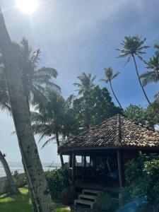 a gazebo on the beach with palm trees at Rockside Cabanas Hotel in Unawatuna