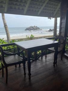 a table and chairs on a porch with a view of the beach at Rockside Cabanas Hotel in Unawatuna