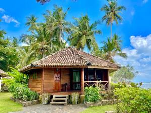a small wooden house with palm trees in the background at Rockside Cabanas Hotel in Unawatuna
