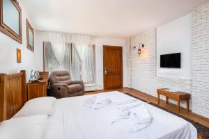 a bedroom with a large white bed and a chair at Ephesus Lodge in Kirazli