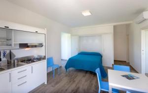 a room with a bed and a kitchen with blue chairs at Conero Infinito in Numana