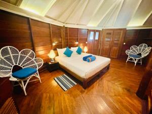 a bedroom with a bed with blue pillows and two chairs at Rockside Cabanas Hotel in Unawatuna