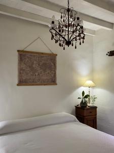 a bedroom with a white bed and a chandelier at Casa Rural El Fortin in Gata