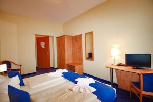 a hotel room with two beds and a desk and a television at Gasthaus Zum Schwan in Oschatz