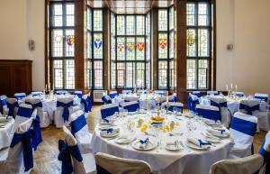 una stanza con tavoli bianchi, sedie blu e finestre di Wellington Hotel by Blue Orchid a Londra