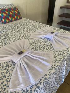 uma cama com dois vestidos brancos em Pousada Princesa do Mar em Tamandaré
