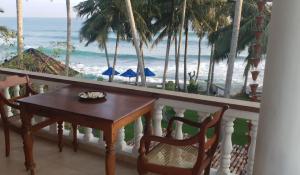 a table and chairs on a balcony overlooking the ocean at Rockside Cabanas Hotel in Unawatuna