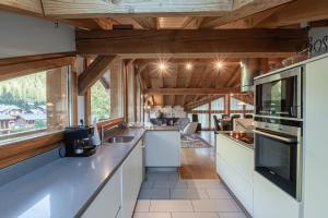 una cocina con armarios blancos y techos de madera. en Chalet Gaia en Chamonix-Mont-Blanc