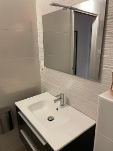 y baño con lavabo blanco y espejo. en Studio cosy avec en option piscine accessible de avril à octobre, en Quimperlé