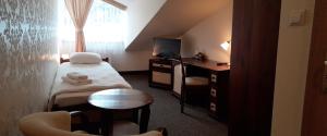 um pequeno quarto com uma cama, uma secretária e uma televisão em Hotel Jaśmin 