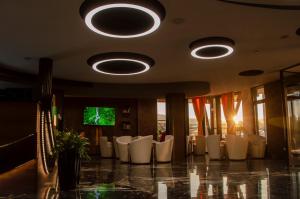 a dining room with white chairs and a flat screen tv at Hotel Biga in Zavidovići