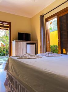 a bedroom with a large bed and a tv at Recanto das Tiribas in Ilhabela