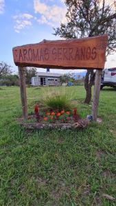 un panneau dans un champ avec des fleurs dans l'herbe dans l'établissement Aromas serranos, à Villa Rumipal