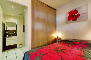 聖吉爾萊班的住宿－Le Vakoa - Saint Gilles les Bains，卧室在床上放着红花