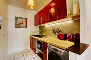 a kitchen with red cabinets and a washing machine in it at Le Vakoa - Saint Gilles les Bains in Saint-Gilles les Bains