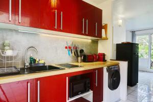 una cucina con armadi rossi, lavandino e lavastoviglie di Le Vakoa - Saint Gilles les Bains a Saint-Gilles-les Bains