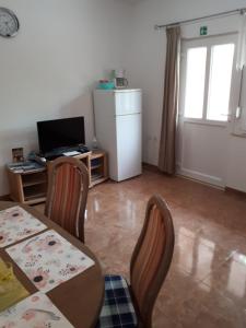 a living room with a table and chairs and a refrigerator at Apartman Laura in Kaštela