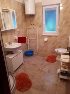 a bathroom with a sink and a toilet and a window at Apartman Laura in Kaštela