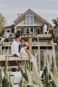 a family sitting on a dock in front of a house at Beach Resort Makkum in Makkum
