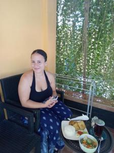a woman sitting in a chair with a plate of food at Juda Homestay in Banyuwangi