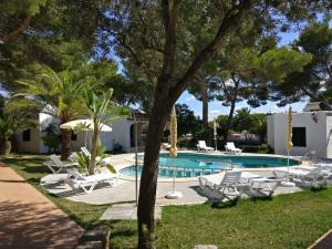 a swimming pool with lounge chairs and a resort at Apartamentos Playa Calan Blanes in Cala en Blanes
