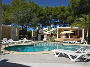a swimming pool with lounge chairs and a house at Apartamentos Playa Calan Blanes in Cala en Blanes