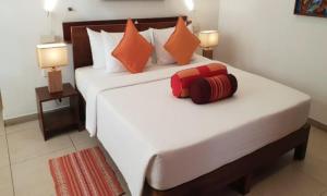 a bedroom with a large white bed with orange pillows at Rockside Cabanas Hotel in Unawatuna