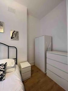 a bedroom with a white bed and a dresser at Stay in the heart of Soho in London