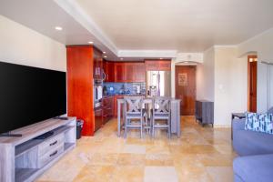 a living room with a large television and a kitchen at Four Paddle Condominium 2210 Thirty plus night rental in Honolulu