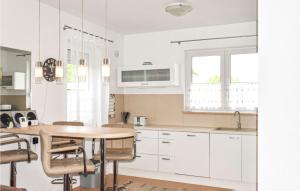 a kitchen with white cabinets and a wooden table at Awesome Home In Wrzosowo With 2 Bedrooms And Wifi in Wrzosowo