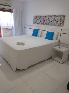 a bedroom with a large white bed with blue pillows at Aconchego Taperapuan Residencial Mont Carmelo in Porto Seguro