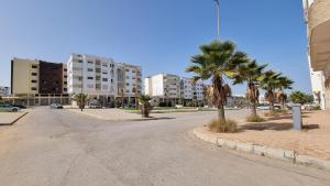 uma rua vazia com palmeiras e edifícios em My Cosy Place Rabat - Cosy Home Wifak Temara em Temara