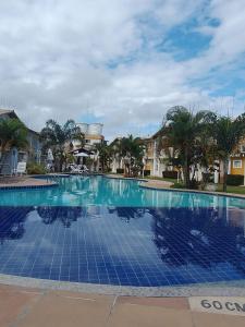 a large swimming pool with blue tiles on it at Aconchego Taperapuan Residencial Mont Carmelo in Porto Seguro
